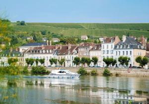 a boat on a river in front of buildings at Cocon Bois-Joly in Joigny