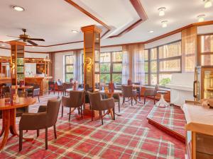 un restaurant avec des tables, des chaises et un piano dans l'établissement Mercure Hotel Bad Duerkheim An Den Salinen, à Bad Dürkheim