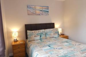 a bedroom with a bed and two night stands with lamps at Two Bedroomed Holiday Cottage with Sea Views in St Austell