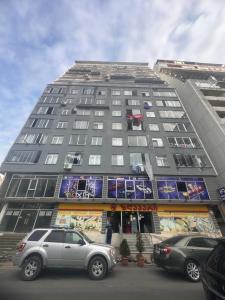 un edificio alto con coches estacionados frente a él en batumi apartament en Batumi
