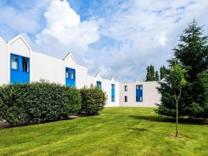 a row of white houses with blue windows at ibis budget Châtellerault Nord in Châtellerault