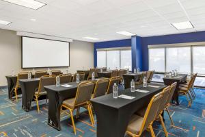une salle de conférence avec des tables, des chaises et un écran dans l'établissement Hampton Inn Mebane, à Mebane