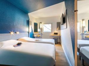 2 łóżka w pokoju z niebieskimi ścianami w obiekcie ibis budget Sucy en Brie w mieście Sucy-en-Brie