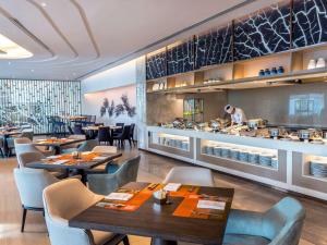 a restaurant with tables and chairs and a chef preparing food at Novotel Phuket City Phokeethra in Phuket Town