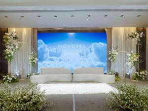 a stage with two white couches in front of a screen at Novotel Phuket City Phokeethra in Phuket Town