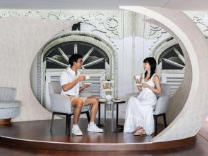 a man and a woman sitting at a table in a room at Novotel Phuket City Phokeethra in Phuket Town