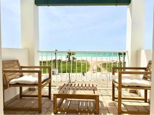 dwa krzesła i ławka na balkonie z widokiem w obiekcie Santa Barbara B Beach front with terrace, sea view in and garage in Conil w mieście Conil de la Frontera
