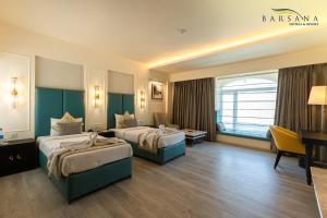 a hotel room with two beds and a desk at Barsana Hotel & Resort Siliguri in Siliguri