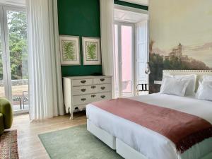 a bedroom with a white bed and a green wall at Solar dos Cantos Botanic House & Garden in Ponta Delgada