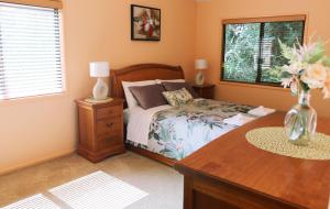 Un dormitorio con una cama y una mesa con un jarrón de flores en Rainforest Cabin in Doon Doon NSW, 