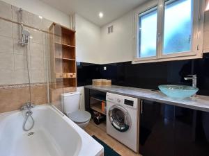 y baño con bañera, lavabo y lavadora. en Appart - proche gare - 4 pers, en Vaucresson