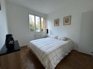 Un dormitorio blanco con una cama y una ventana. en Appart - proche gare - 4 pers, en Vaucresson