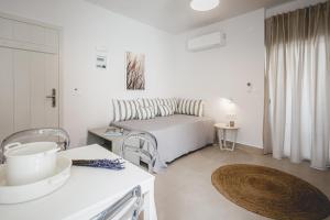een witte slaapkamer met een bed en een tafel bij Votsalo Tolo in Tolo