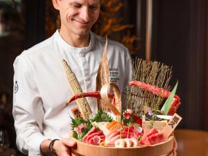 un chef está sosteniendo una cesta de comida en Hôtel Le Royal Monceau Raffles Paris en París