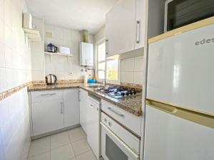 kuchnia z białymi szafkami i lodówką w obiekcie Santa Barbara B Beach front with terrace, sea view in and garage in Conil w mieście Conil de la Frontera