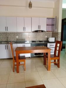 een keuken met een houten tafel en 2 stoelen bij KIM UNIVERSITY TWO ROOMS APARTMENT in Kigali