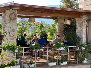 un grupo de personas sentadas en un restaurante bajo una pérgola en Arial Penthouse Suites, en Vlorë