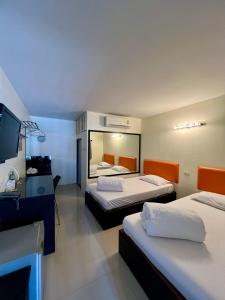 a hotel room with two beds and a television at Ngeeb bed and EV station in Chiang Rai