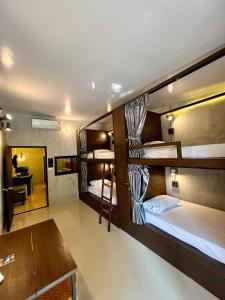 a room with three bunk beds and a desk at Ngeeb bed and EV station in Chiang Rai