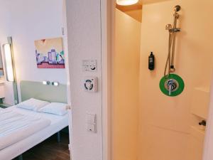 a small room with a bed and a shower at ibis budget Berlin Ost in Berlin