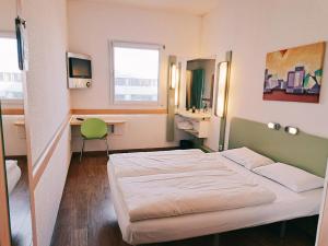 ベルリンにあるibis budget Berlin Ostのベッドとデスクが備わるホテルルームです。