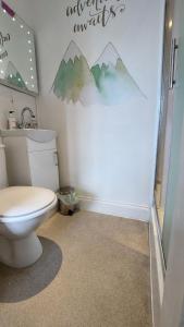 a bathroom with a toilet and mountains on the wall at Invergarry Room Only Guest House For Adults in Windermere