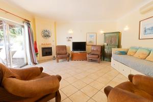 uma sala de estar com uma cama e cadeiras e uma televisão em Urban Beach - Casa MM em Carvoeiro