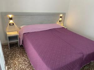 un letto viola in una camera da letto con tavolo e luci di MADONNA BB a Milano Marittima