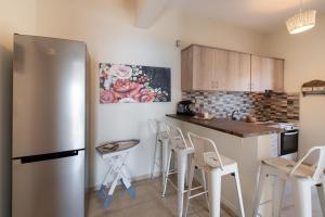 a kitchen with a stainless steel refrigerator and white stools at Meteora Suites in Nikiana