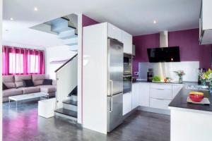 a kitchen with white cabinets and purple walls at Designer Haus mit beheiztem Pool (überdacht) in La Listada