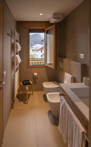bagno con servizi igienici, lavandino e finestra di Chalet Cridola Dolomiti Experience a Lorenzago