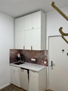 a kitchen with white cabinets and a sink at Gemütliche Wohnung nur 15 Minuten ins Stadtzentrum in Vienna