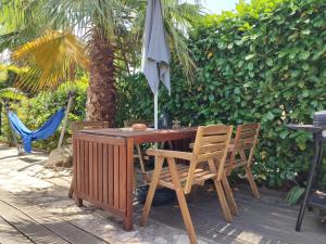 a wooden table with two chairs and an umbrella at Villa club avec jardin in Bandol