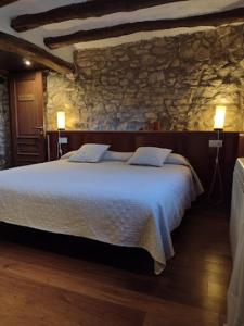 Masia Serret في أغير: غرفة نوم بسرير كبير في جدار حجري