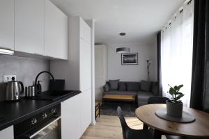 a kitchen and a living room with a table at Pure Elegance Apartament in Gdynia