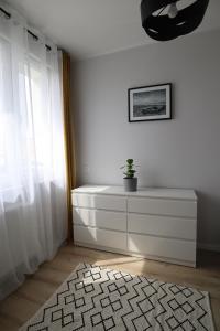 una stanza bianca con un comò con una pianta sopra di Pure Elegance Apartament a Gdynia