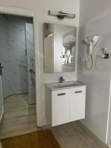 La salle de bains blanche est pourvue d'un lavabo et d'un miroir. dans l'établissement Chez Ali Apartments, à Essaouira