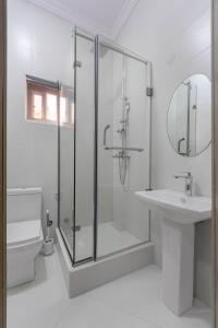 a white bathroom with a shower and a sink at Firenze Apartments Lekki in Lagos