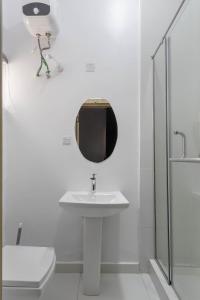 a white bathroom with a sink and a mirror at Firenze Apartments Lekki in Lagos