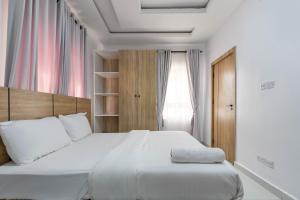 Un dormitorio con una gran cama blanca y una ventana en Firenze Apartments Lekki en Lagos