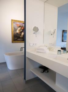 ein Badezimmer mit einer Badewanne, einem Waschbecken und einem Spiegel in der Unterkunft Hotel & Restaurant Posthalterei in Zusmarshausen