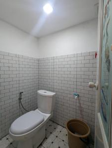 a bathroom with a toilet in a white tiled room at Cottage Linggayoni Dieng in Diyeng +37 photos