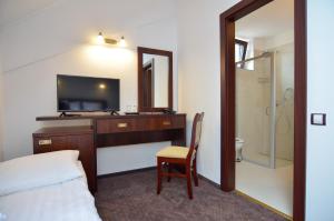 a hotel room with a bed and a desk with a television at Taverna Olteanului in Ranca