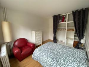 een slaapkamer met een bed en een rode stoel bij Lovely Flat 4 peoples in Saint-Cloud