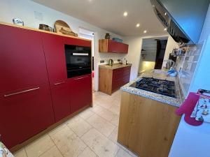 een keuken met rode kasten en een fornuis met oven bij Am Ampferang:Ferienhaus in Ettal in Ettal