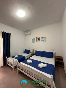 duas camas num quarto com azul e branco em Vogue Rooms em Golem