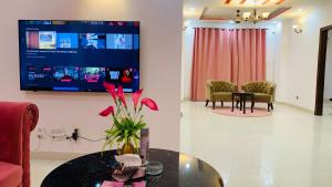 - un salon avec une table et une télévision murale dans l'établissement Serene Home Apartment, à Islamabad