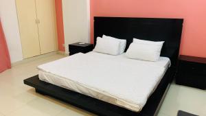 - une chambre avec un grand lit et une tête de lit noire dans l'établissement Serene Home Apartment, à Islamabad