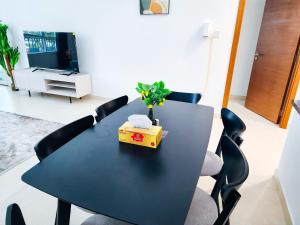 a black dining room table with chairs and a tv at Harf303 Fancy 1BR w big balcony at Ansam , Yas Island in Abu Dhabi