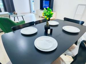 a black table with white plates and a vase with flowers at Harf-G13 Fancy 1BR w big balcony at Ansam , Yas Island in Abu Dhabi